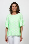 Top Ligne Neon Flowers Flounce Tee in Green. Green textured velour flours on a white background. Crew neck tee with elbow length sleeve with ruffled cuff. A line shape. Relaxed fit._t_35730168316104