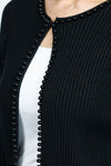 Metric Ribbed Cardi with Pearl Detail in black.  Vertical ribbed Open front knit with crew neck and single hook and eye closure.  Black pearl trim around neck and front.  Long sleeves. Dropped shoulder.  Classic fit._t_52919152673134