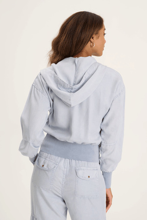 XCVI Karney Bomber in Spry Blue a light blue.  Zip front with attached hood and drawstring.  Long sleeves.  Ribbed banded hem and cuff.  Brushed twill body.  2 chest pockets with zipper closure.  Relaxed fit._59588992237934