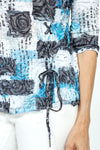 Top Ligne Brushed Patches Grommet Crinkle Top. Light blue, black and white brushed screen printed patches over a jacquard rose print background. V neck 3/4 sleeve top. Grommet and lace tie in black at left front. Black trim at neckline. Crinkle fabric. Relaxed fit._t_35741023437000