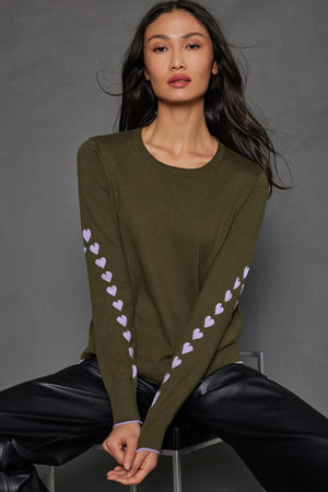 Lisa Todd Love Notes Sweater in Eden, an olive green.  Crew neck long sleeve cotton/cashmere knit.  Lavender intarsia knit hearts wrap around sleeves.  Rib trim at neck, hem and cuff.  Lavender tipping at hem and cuff.  Relaxed fit._52882964283758