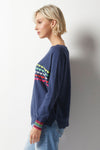 Zaket & Plover Love Struck Sweater in Denim. Boat neck with long dolman sleeves. Knit side to side. Rainbow stripes of intarsia hearts in front. Rainbow stripes on sleeve cuff. Rib trim at hem and cuff. Relaxed fit._t_36033739063496